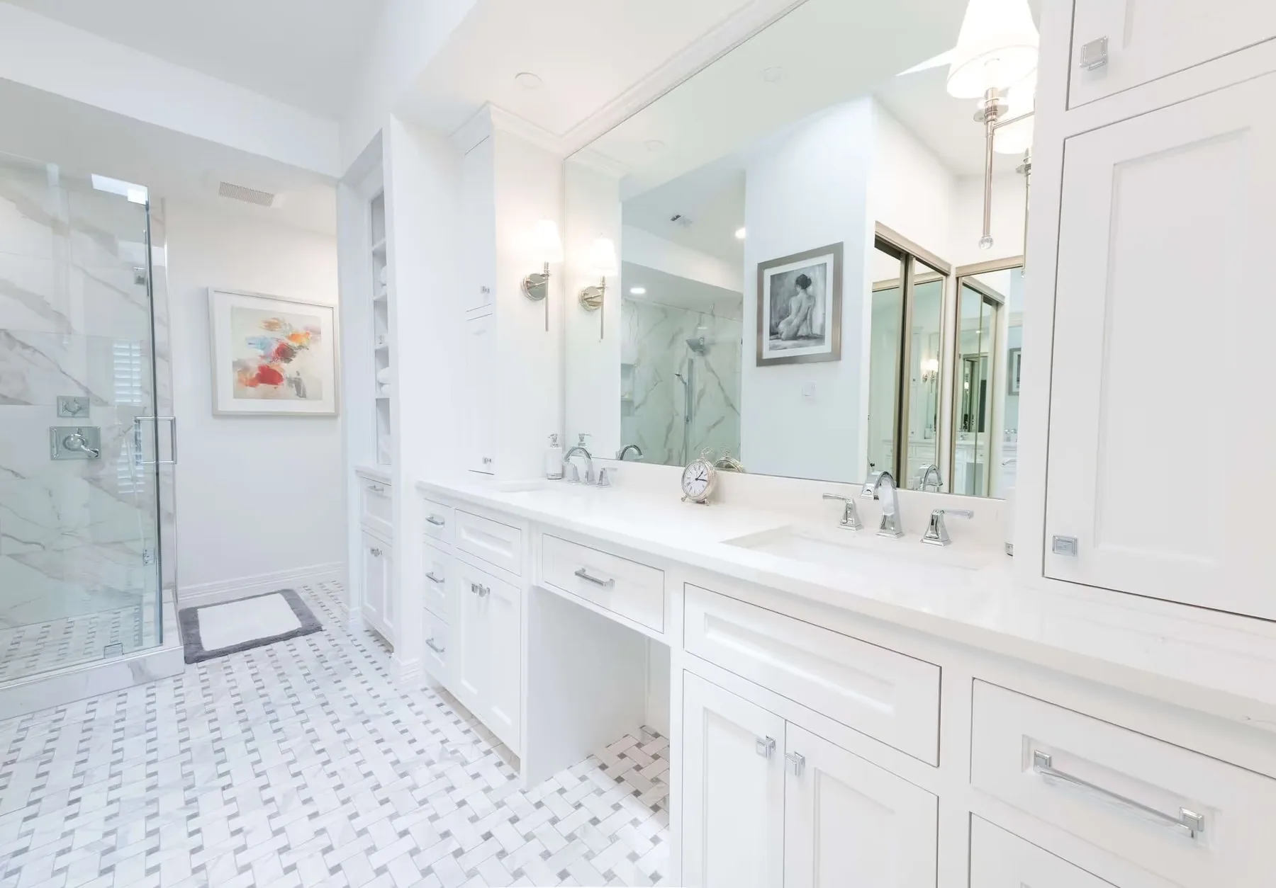 A primary bathroom with a double vanity, marble basketweave floor and a glass shower