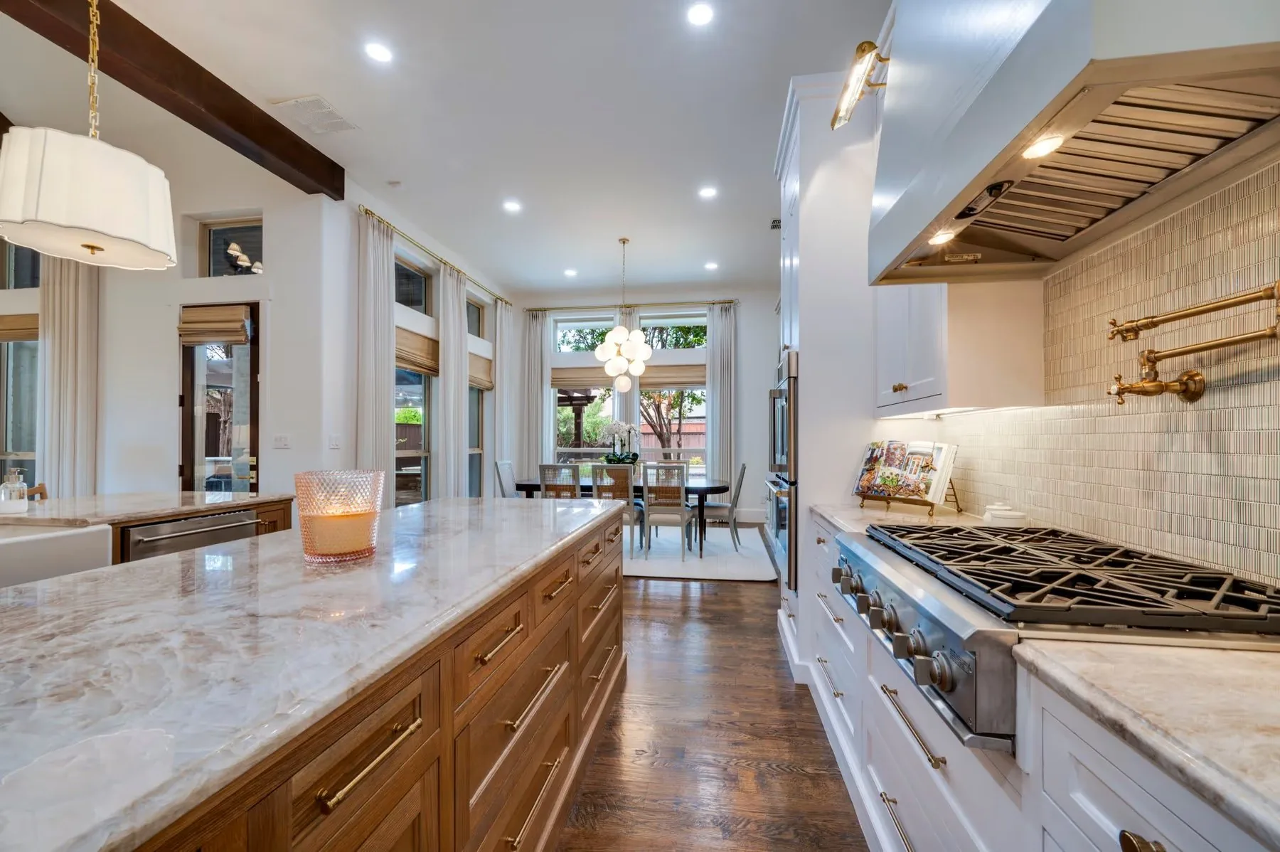 A kitchen with a quartzite island, oak cabinetry and a brass pot filler